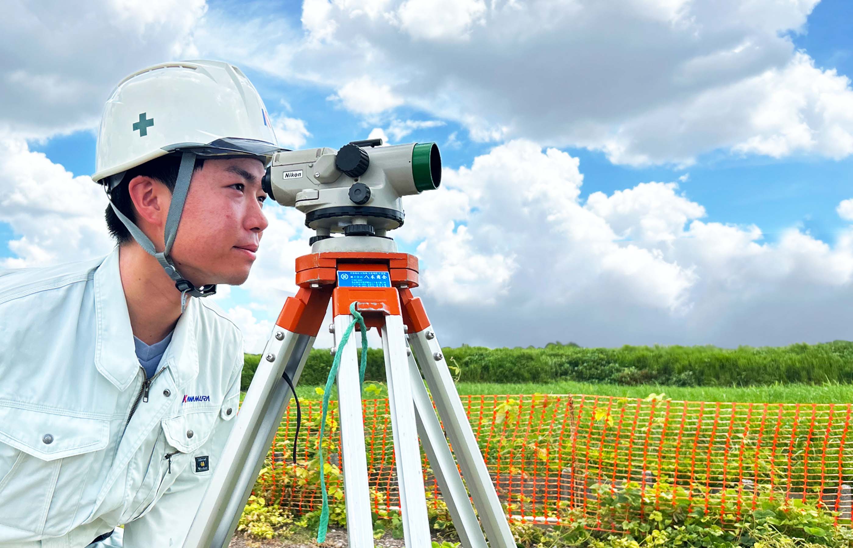 測量機器のレンズを覗く建設事業部の作業員